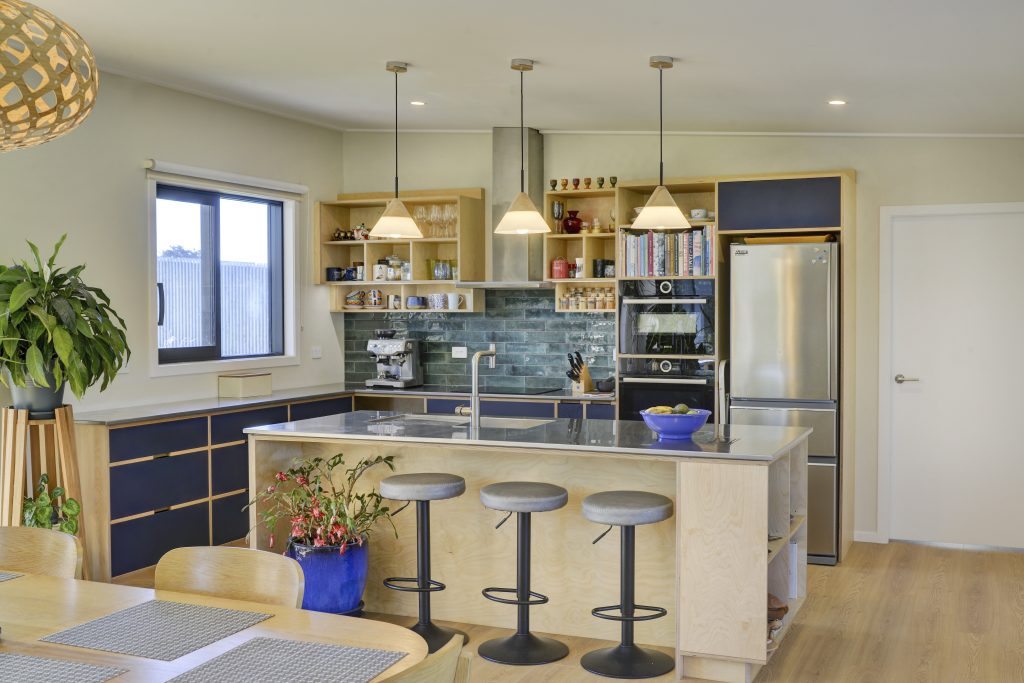 A newly built open plan dining and kitchen space with modern wooden flooring and dark kitchen cabinetry