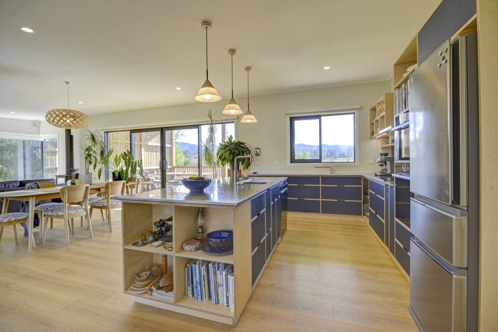 A newly built open plan dining and kitchen space with modern wooden flooring and dark kitchen cabinetry