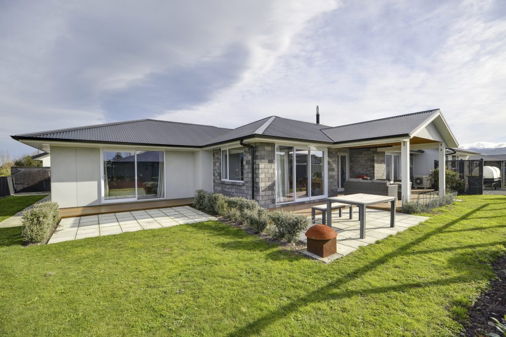 The rear yarn of a freshly built modern brick home with a well-tended garden.