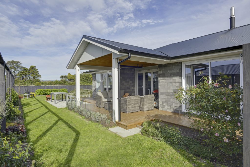The rear yarn of a freshly built modern brick home with a well-tended garden.