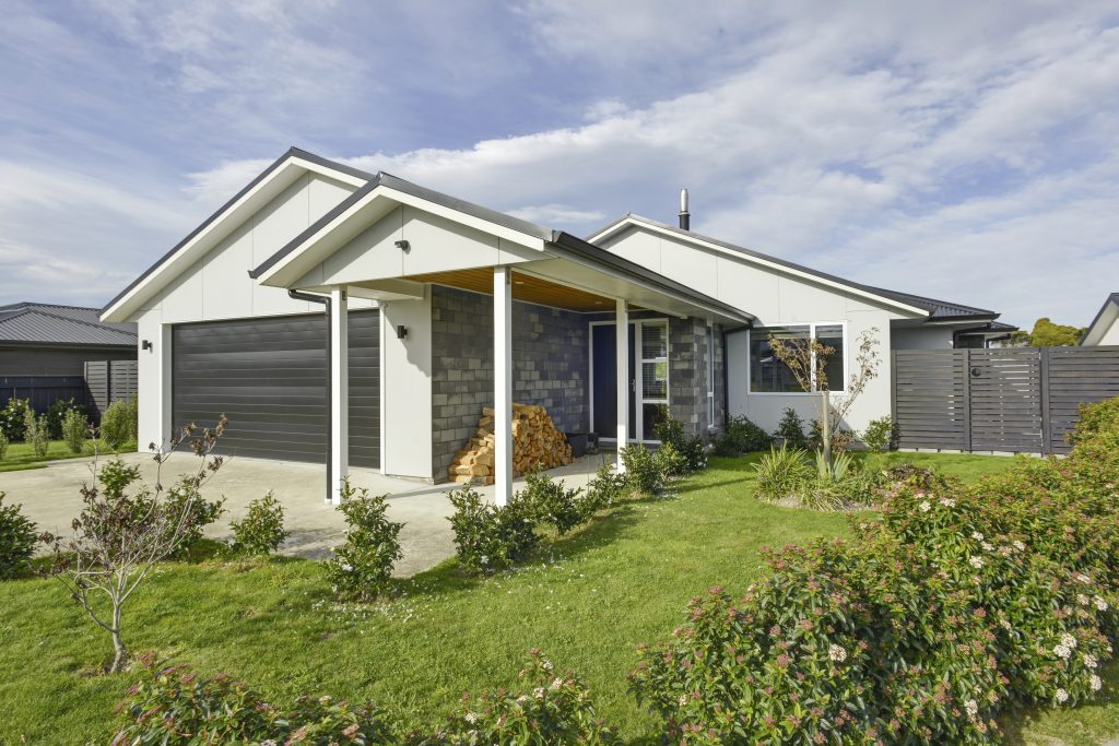The frontage of a freshly built modern brick home with a garage and well-tended garden.
