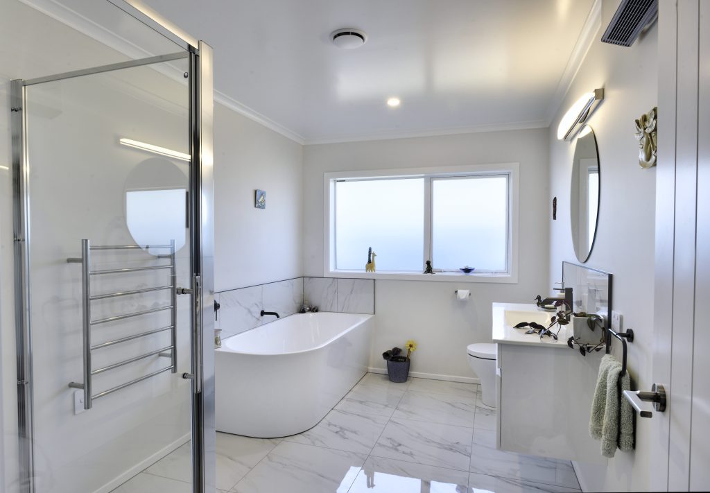 A modern marble floored white bathroom with large bath and walk-in shower