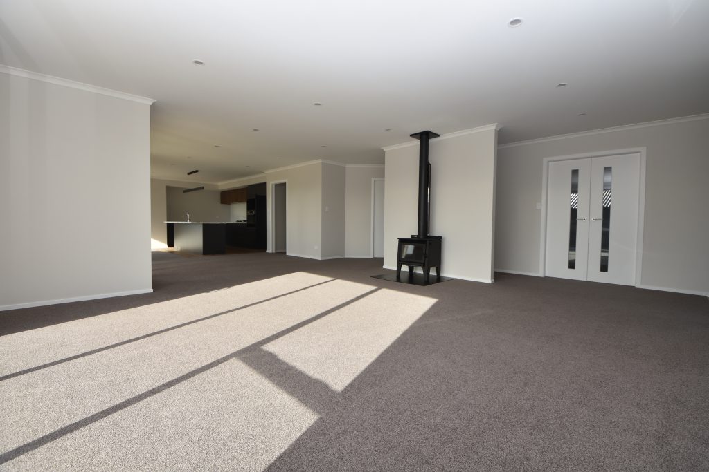 A freshly built and empty open-plan living space with free standing wood burner fireplace