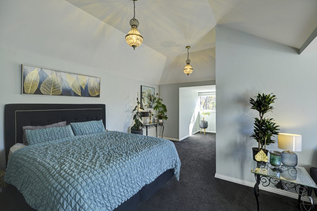 A recently decorated master bedroom following a recent renovation. The room is classically styled with large double bed and ornate occasional furniture.