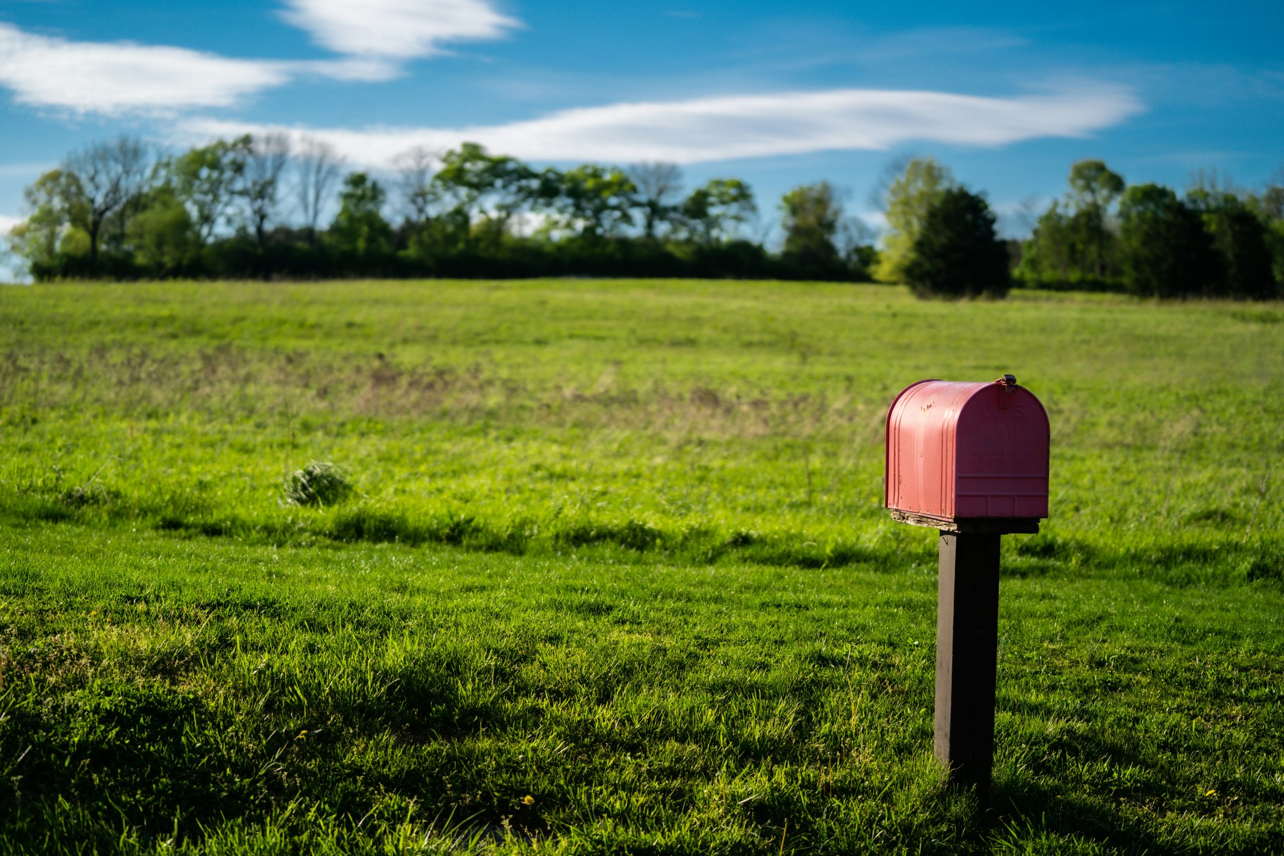A red mail box on an empty piece of grassy land, urging the viewer to contact WDG